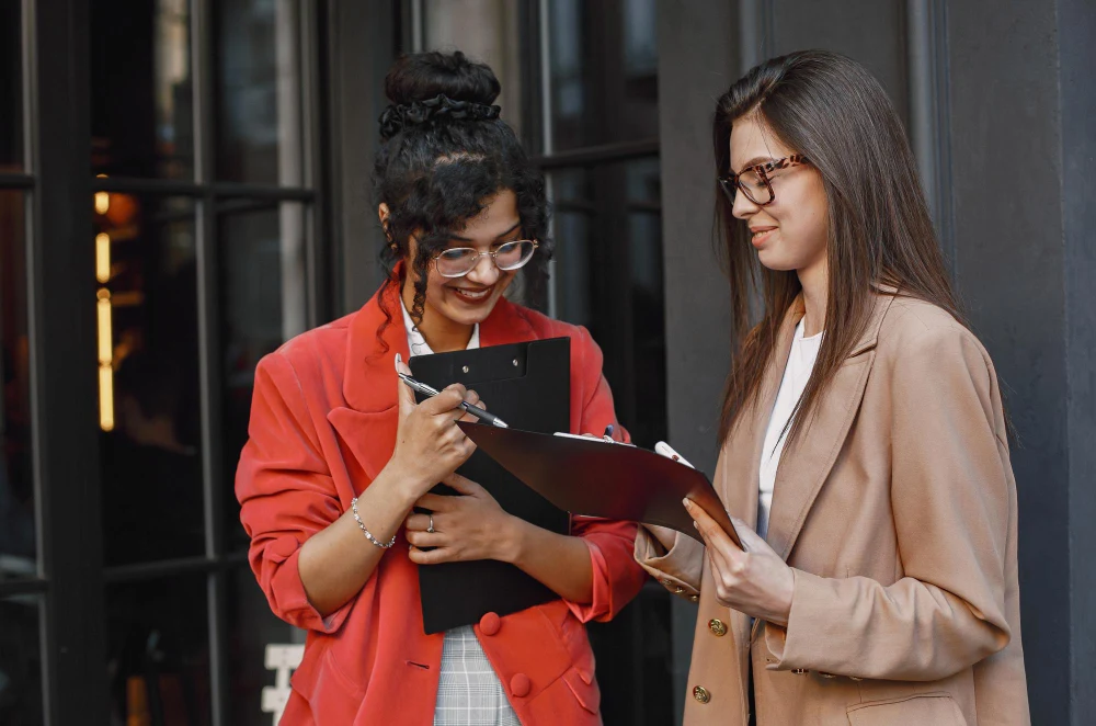 Two businesswomen discussing documents with smiles