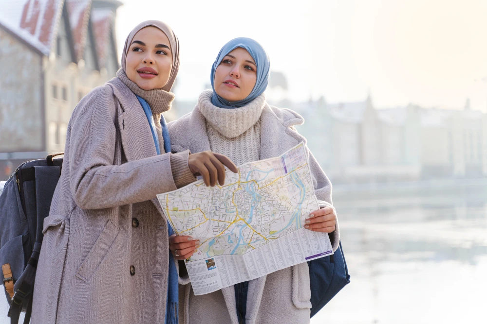 Two Muslim women tourists with a city map, exploring travel destinations abroad.