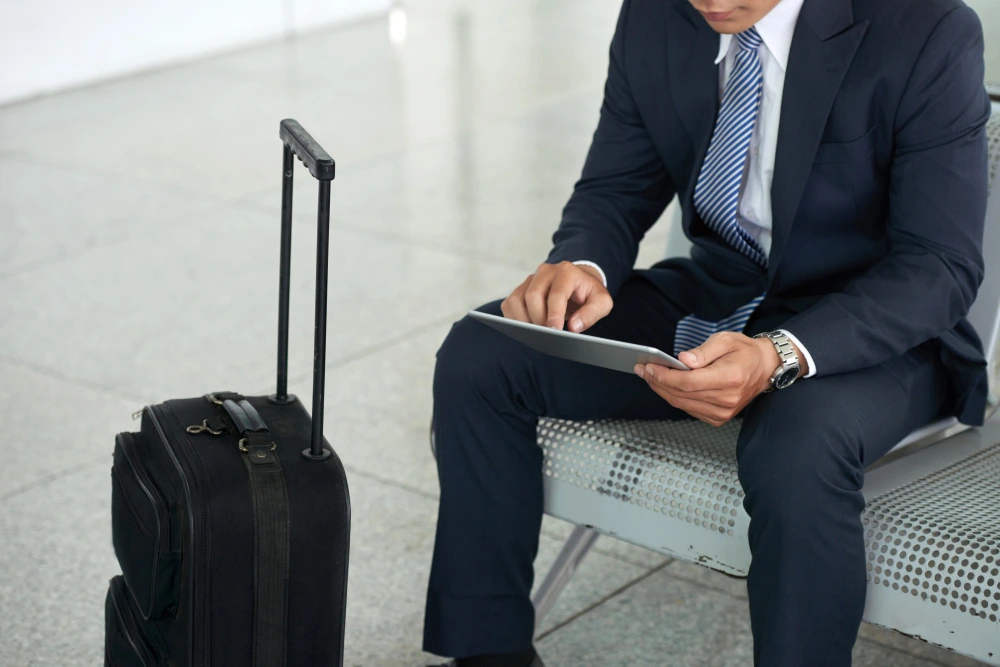 Professional business traveler with luggage using tablet